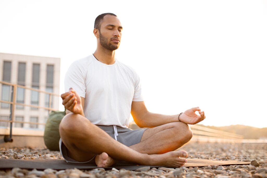handsomemalemeditatinginlotuspositionwhilesittingonmat